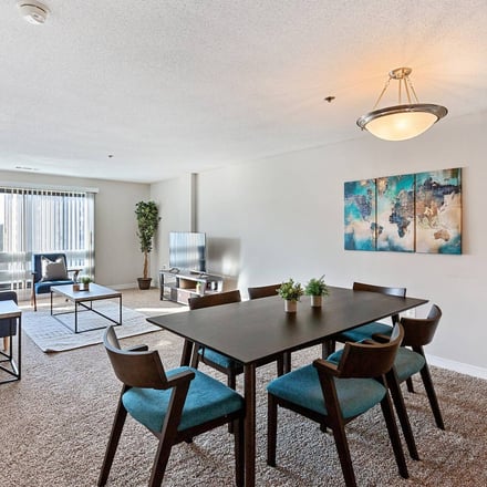 Open dining and living area with teal accent chairs