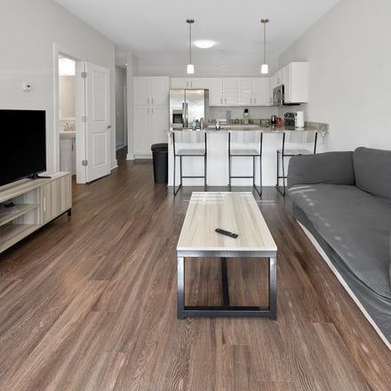 Modern open-plan living room with white kitchen and hardwood floors